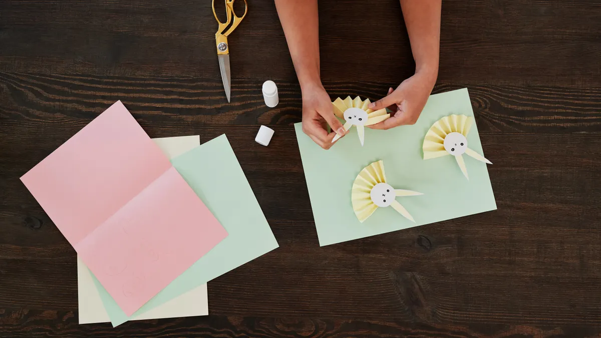 Hands making paper decorations with scissors and colored paper
