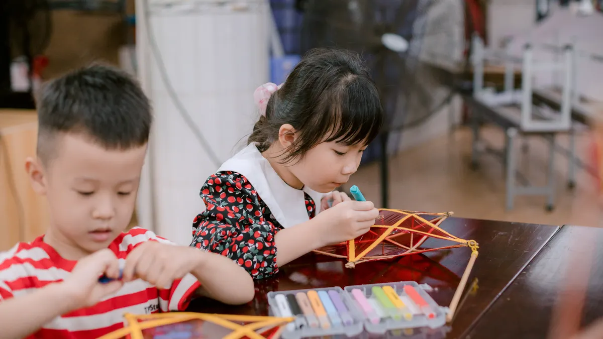 Children building stick crafts at a table