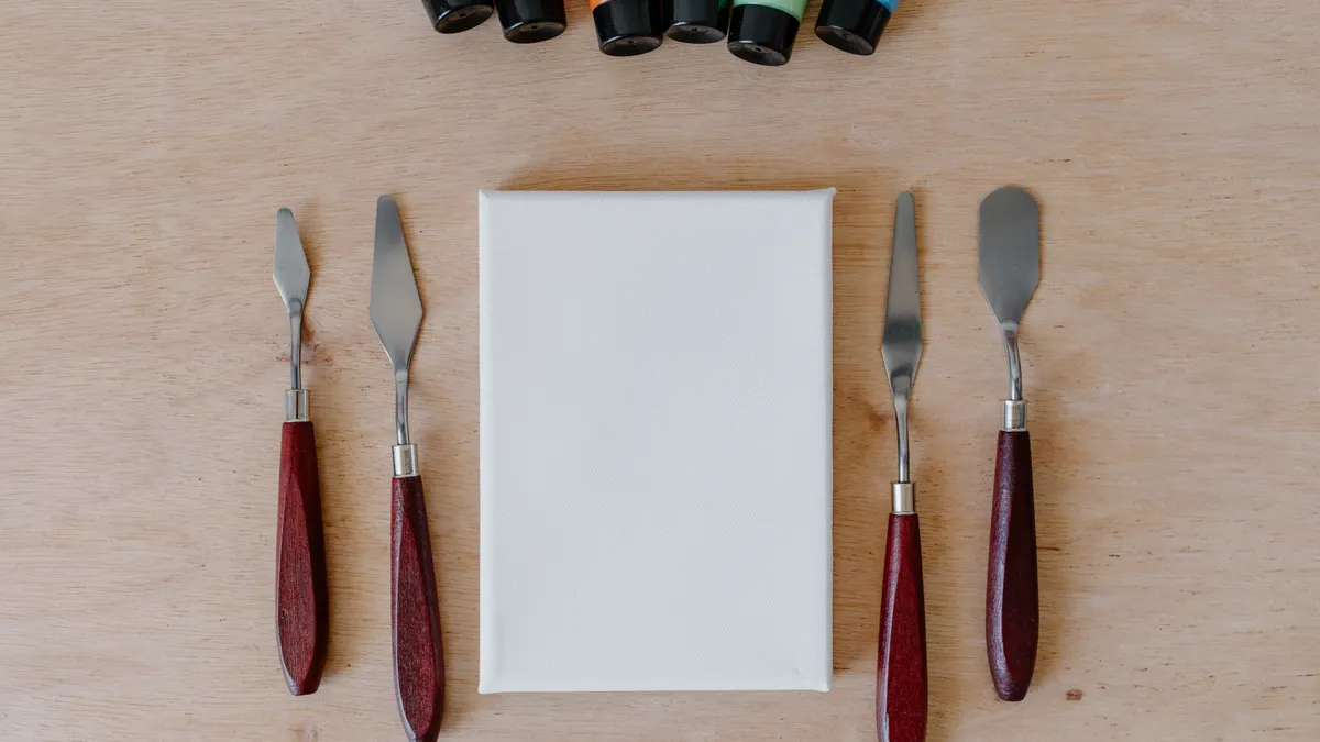 Blank canvas with paint tubes and palette knives