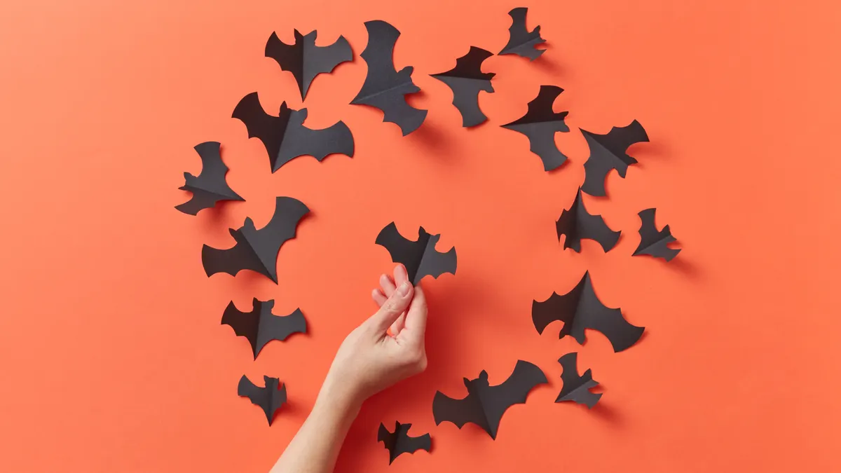 Hand arranging paper bats in a circle