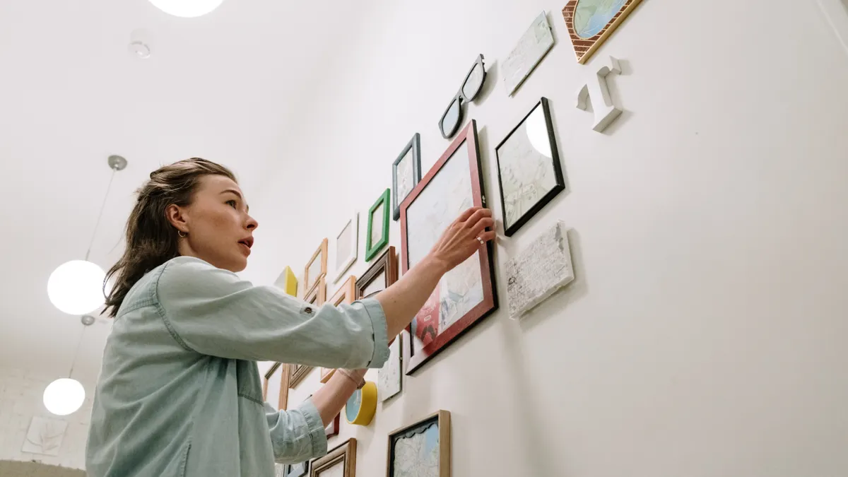 Person hanging framed art in a gallery wall