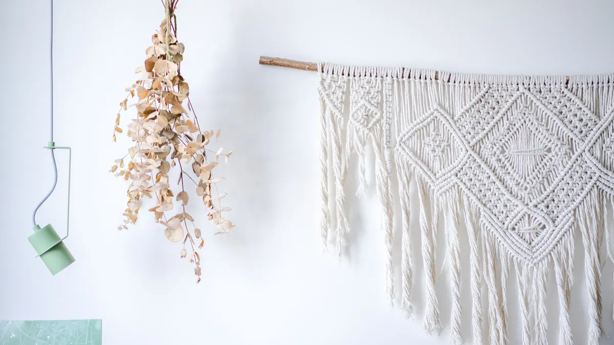 White macrame wall hanging with fringe on a wall