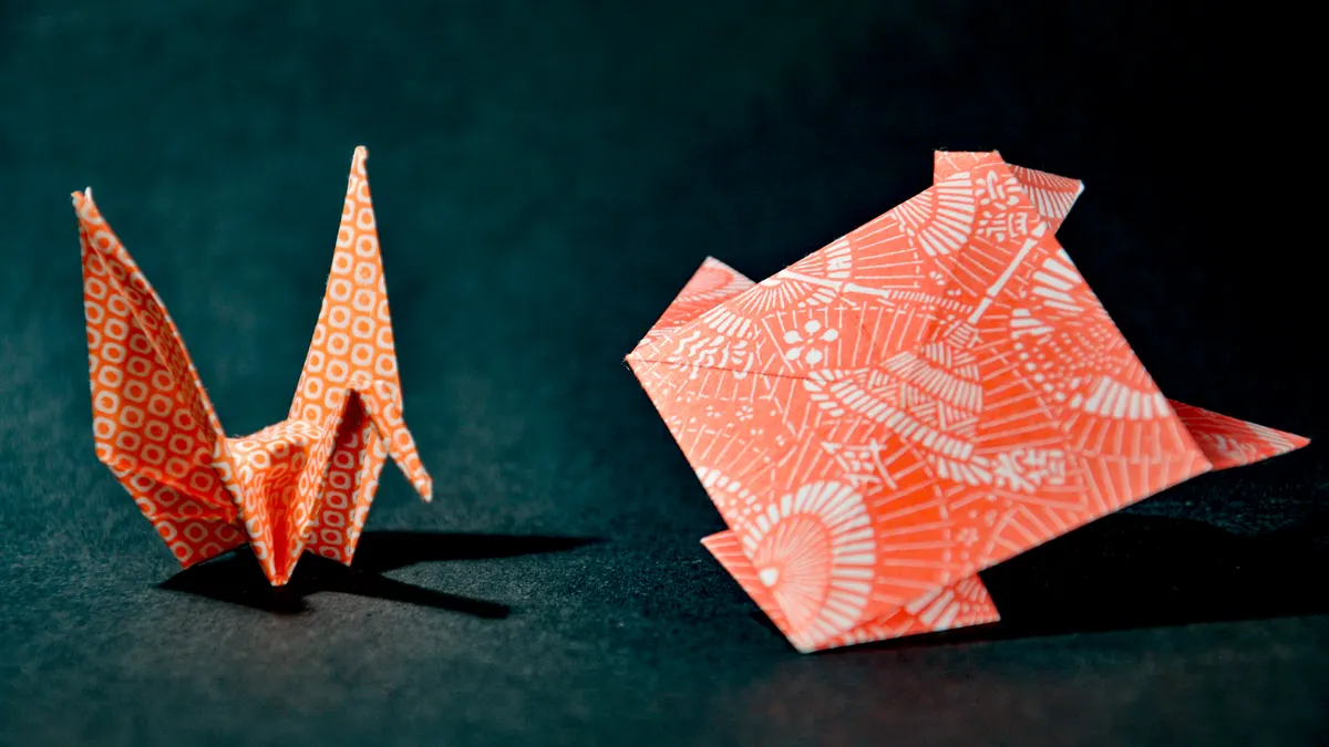 Two patterned origami cranes on dark background