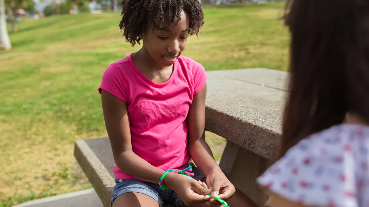 Girl making a colorful friendship bracelet outdoors