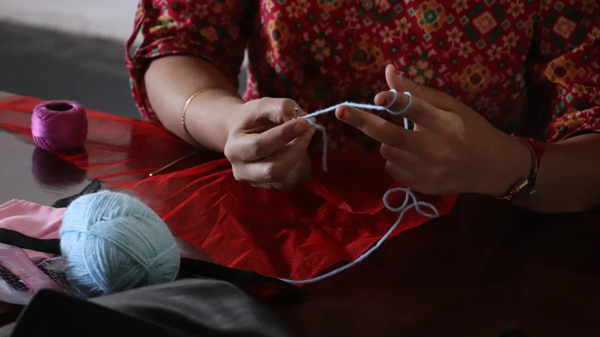 Hands knotting yarn on a table