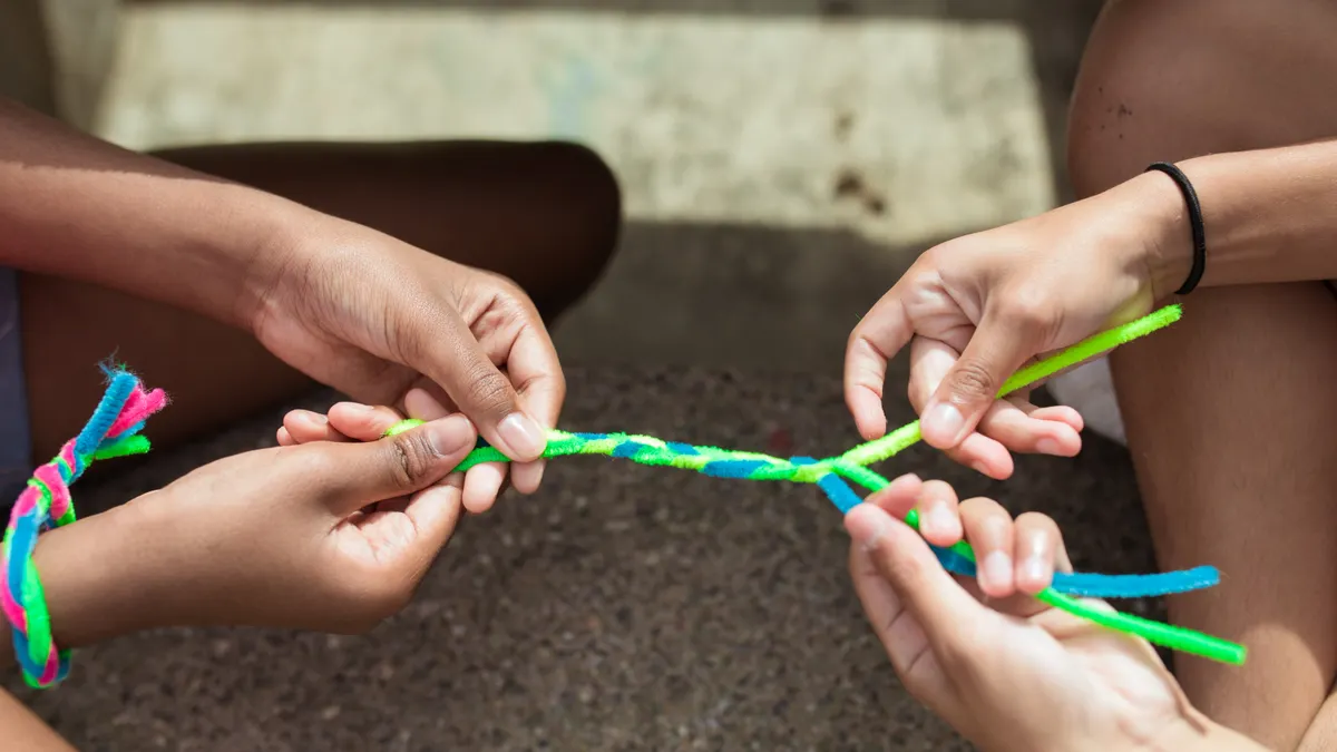Children weaving a colorful yarn friendship bracelet