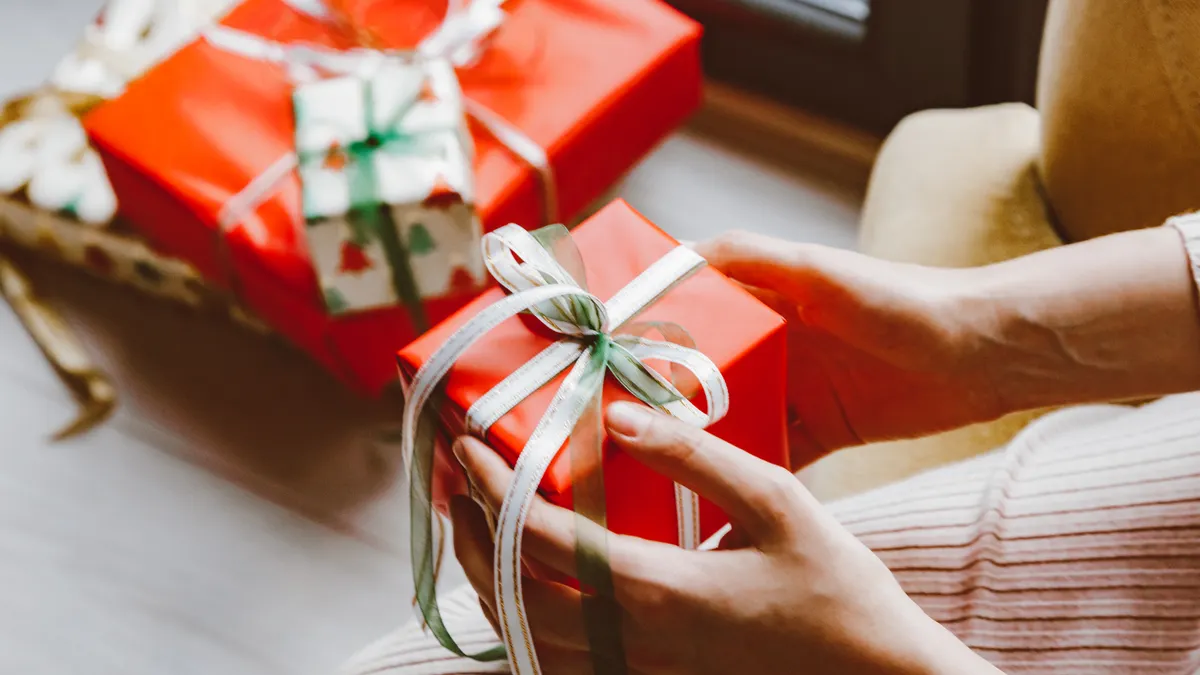 hands wrapping a red gift box with ribbon