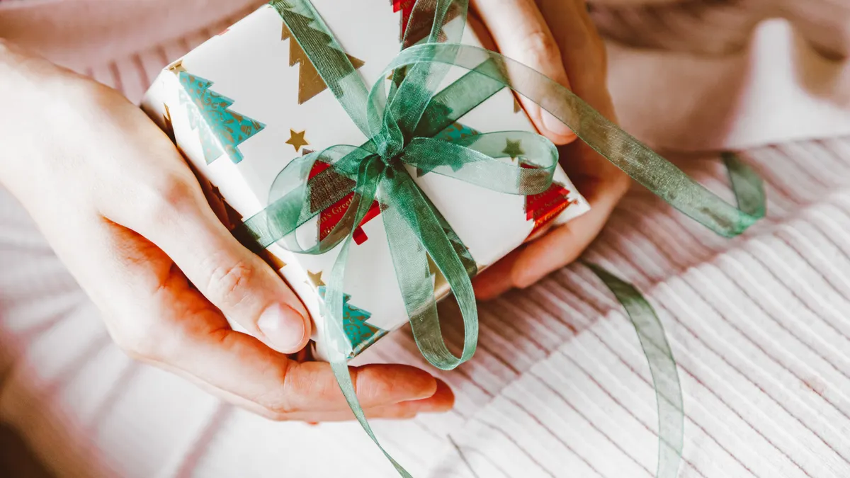 hands holding a wrapped gift box with ribbon